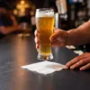 1-Ply White Cocktail Napkin holding a beer